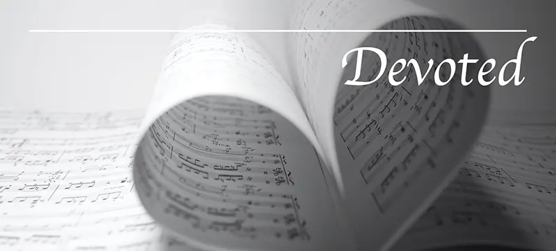 Black and white image of sheet music pages curled into a heart with the word Devoted overtop.
