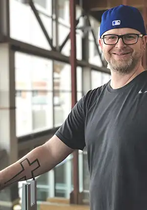 Jon Caldwell showing his forearm tattoo of a cross