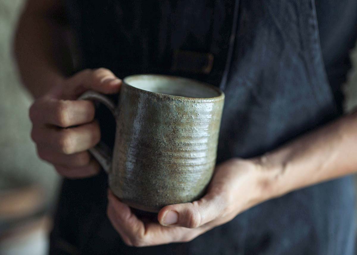 Person holding ceramic mug.